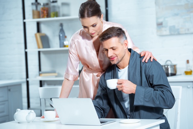 A couple in robes at the kitchen table over breakfast