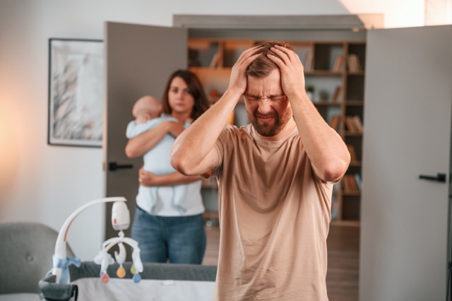 A stressed couple sitting apart, each holding their head