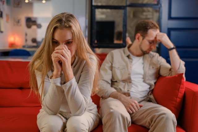 A couple in crisis, sitting separately on the sofa